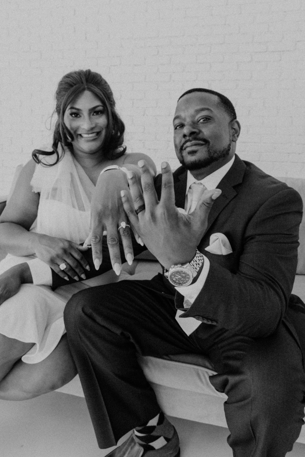Ericka and Alex Gibson showing their rings in a black-and-white portrait